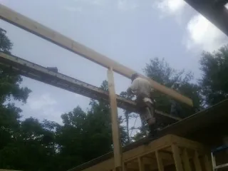 Carpenter setting a ridge beam over a new addition frame — Ice Dam Removal by Roofing Brothers in Scarsdale