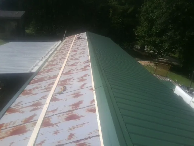 Old rusted panels beside newly installed green metal roofing — Wind Damage Roof Repair by Roofing Brothers in Scarsdale