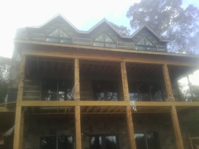 Dormers and porch framing on a large log home under construction — Roof Coating work by our crew in Scarsdale