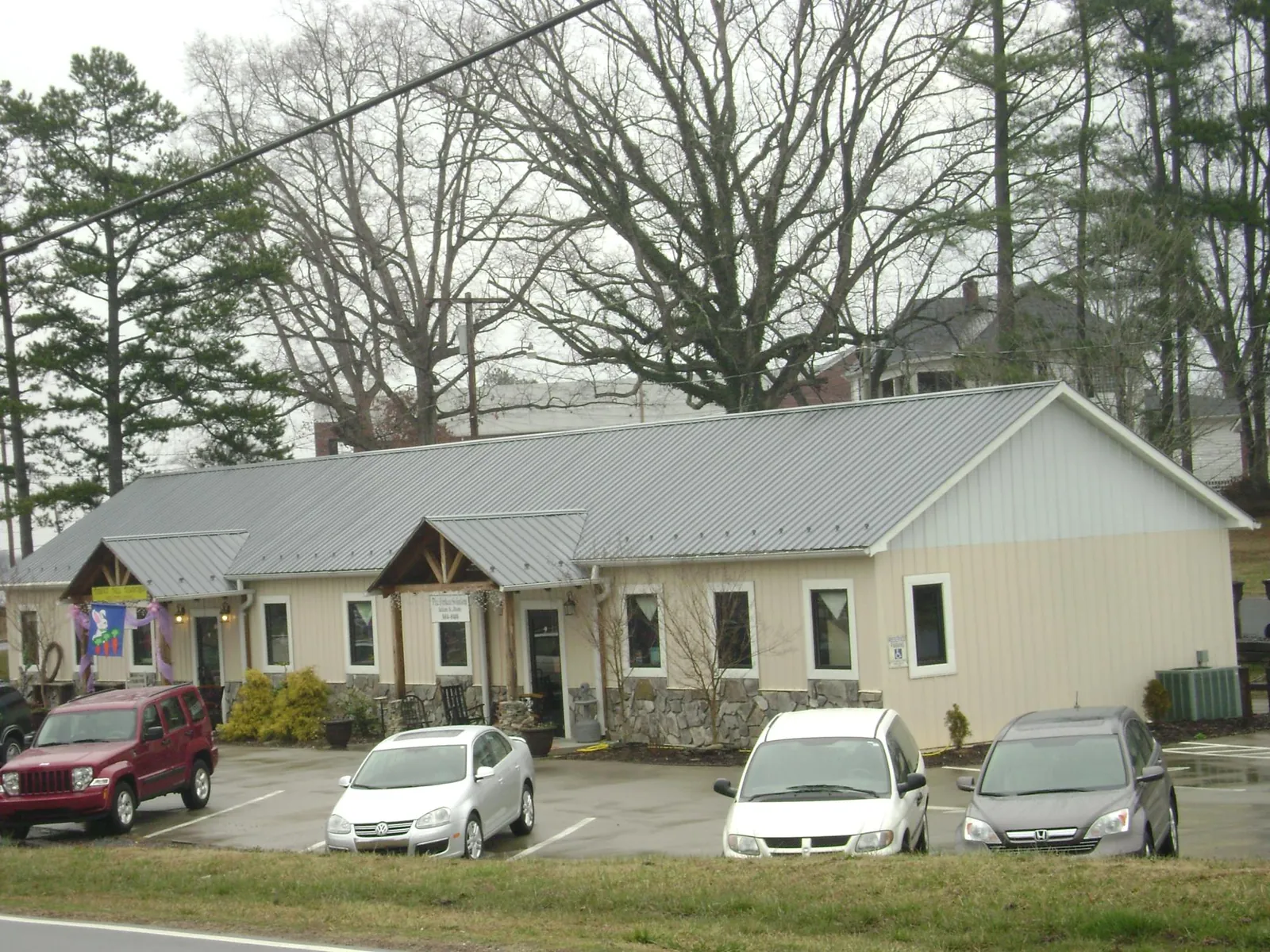Gray metal roof with timber entry brackets on a small commercial building in Scarsdale