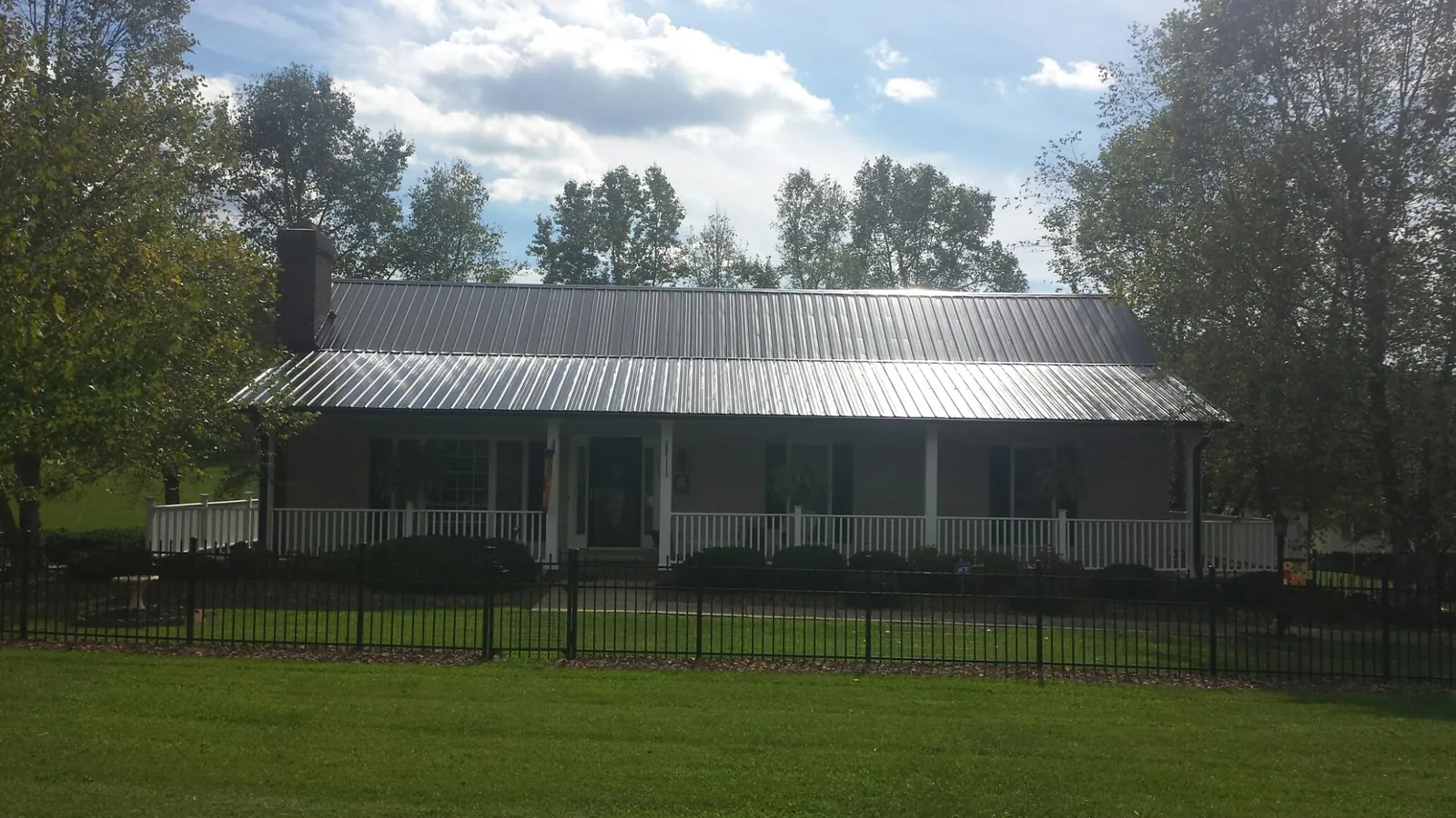 Gray metal roof on a brick ranch with a full width front porch — Gutter Guard Installation work by our crew in Scarsdale