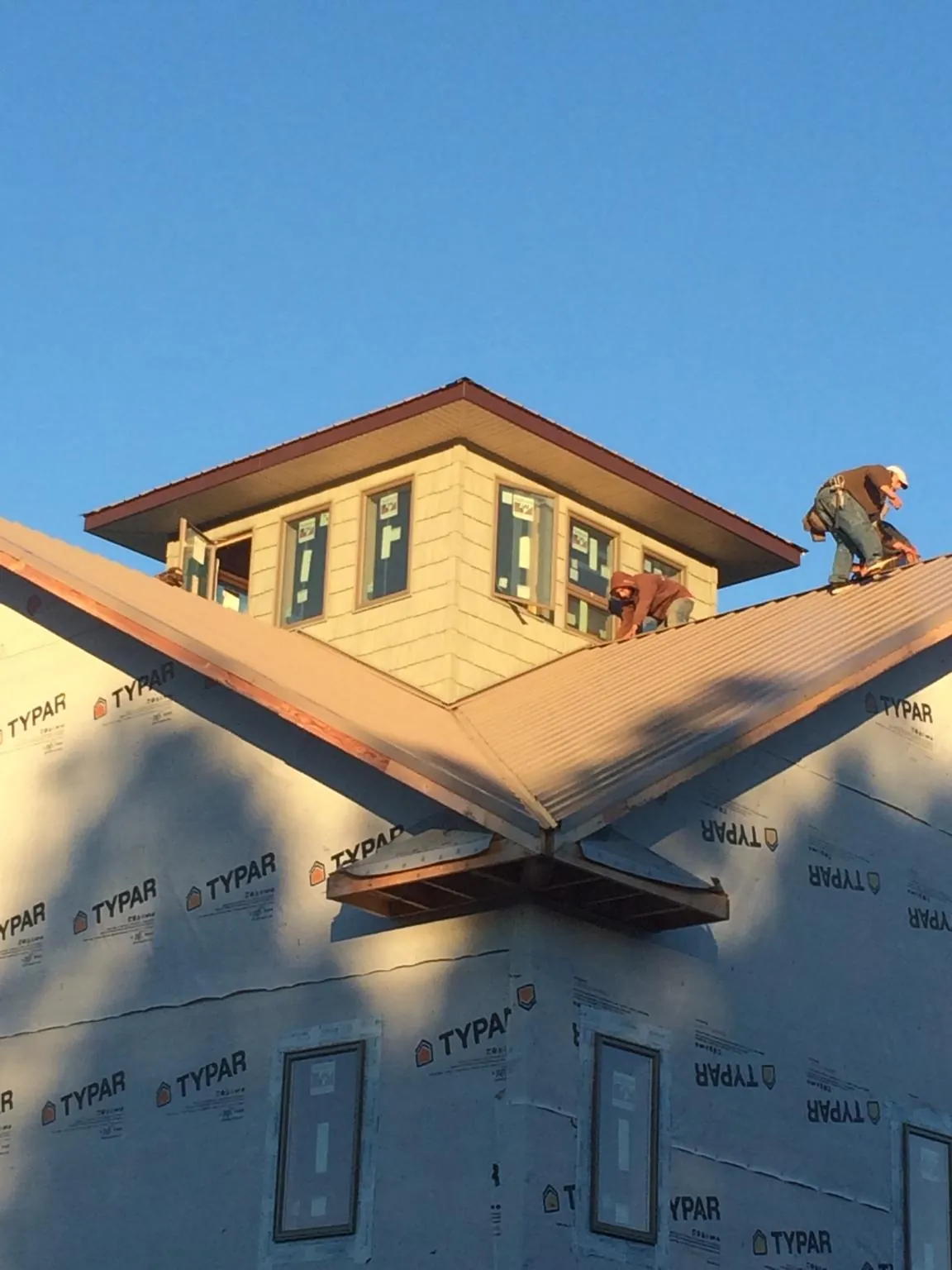 Roofers working around a rooftop cupola on a new metal roof at sunset — Roof Waterproofing in Scarsdale by Roofing Brothers